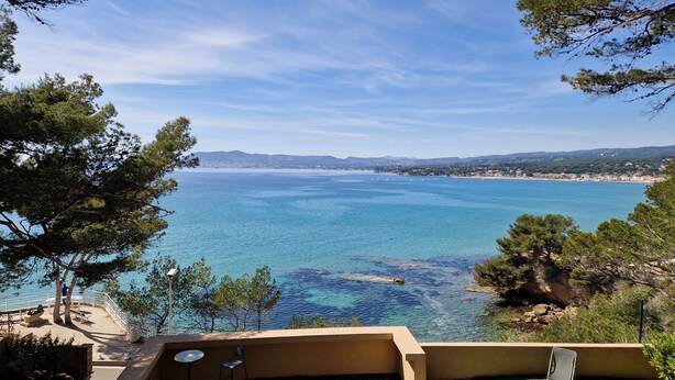 A coastal view with a clear blue sea, a sandy beach, and a rocky shoreline.