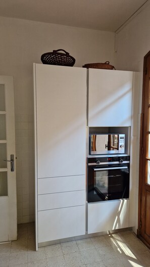 A kitchen with a built-in oven and microwave, a white cabinet, and a basket on top. - Large 6 p. air-conditioned family home with swimming pool on the seafront (Saint-Cyr-sur-Mer)