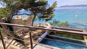 A pool with a clear view of the sea and a stone staircase leading down to the water.