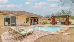 Un jardin avec une piscine, un espace salon extérieur et un coin barbecue.