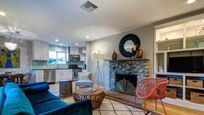 Un salón moderno con un sofá azul, una chimenea de piedra y un televisor sobre un mueble blanco.