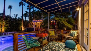 Un espacio al aire libre techado con piscina, asientos y palmeras.