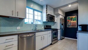 Una cocina moderna con electrodomésticos de acero inoxidable, armarios blancos y un salpicadero de azulejos azules.