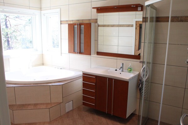A modern bathroom with a bathtub, a large mirror, and a glass shower enclosure.