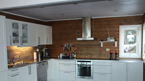A modern kitchen with white cabinets, a stainless steel oven, and a wooden wall. - Great cabin in a central location (Agder)