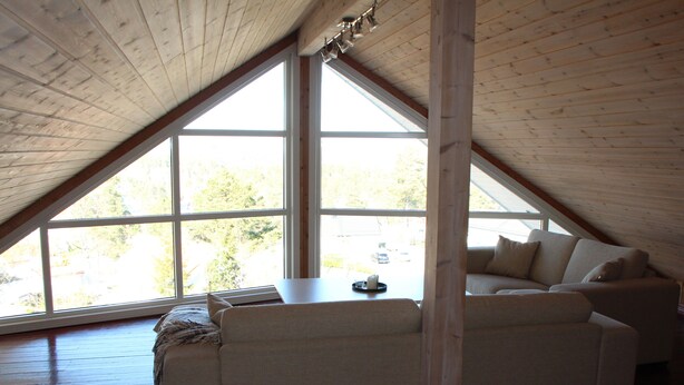 A loft-style room with a sloped ceiling, large windows, and a sofa. - Great cabin in a central location (Agder)