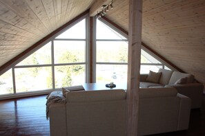 Quarto estilo loft com teto inclinado, janelas amplas e um sofá.