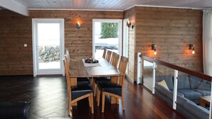 A modern interior with a wooden dining table, black chairs, a sofa, and a glass railing. - Great cabin in a central location (Agder)