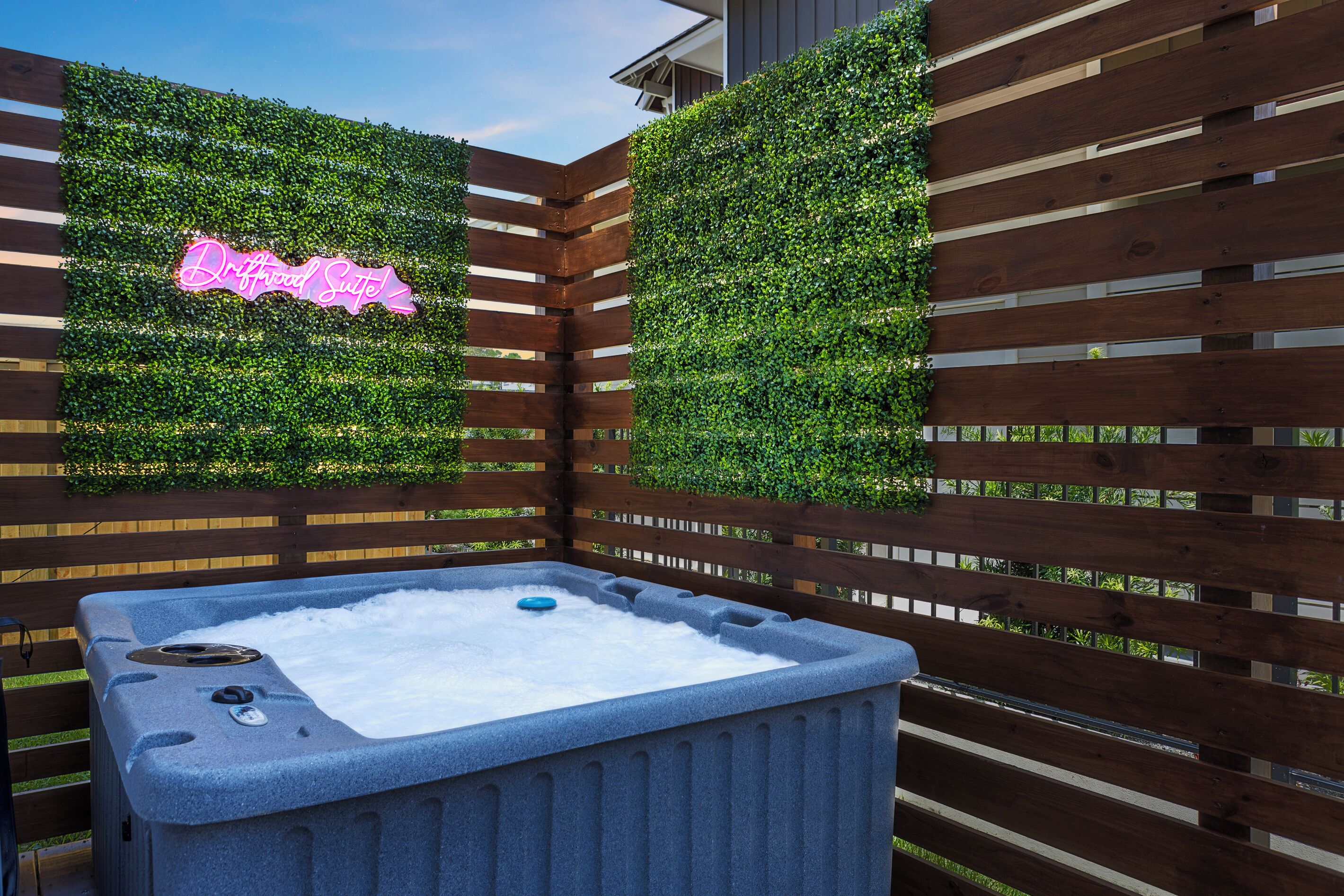 Un jacuzzi rodeado por una valla de madera y follaje.