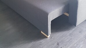 A room with a grey sofa bed against a white wall and grey wooden flooring. - Petite Maison Moderne à la Campagne (Saint-Paulien)