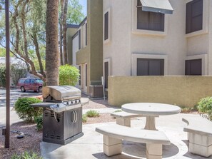 An outdoor patio with a barbecue grill and a table and benches. - Cozy Phoenix Condo Near Biltmore | Pool & BBQ near Golf, Dining and Shops (Phoenix)