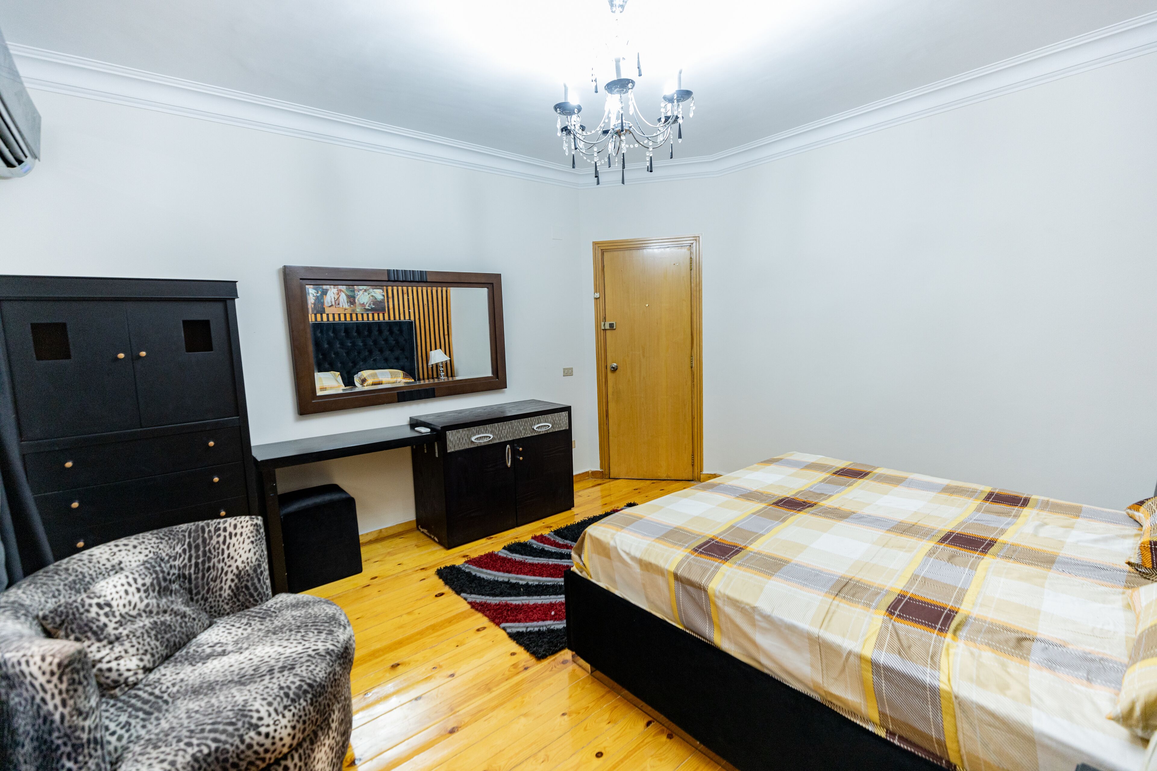 A bedroom with a bed, a desk, a chair, a wardrobe, and a door.