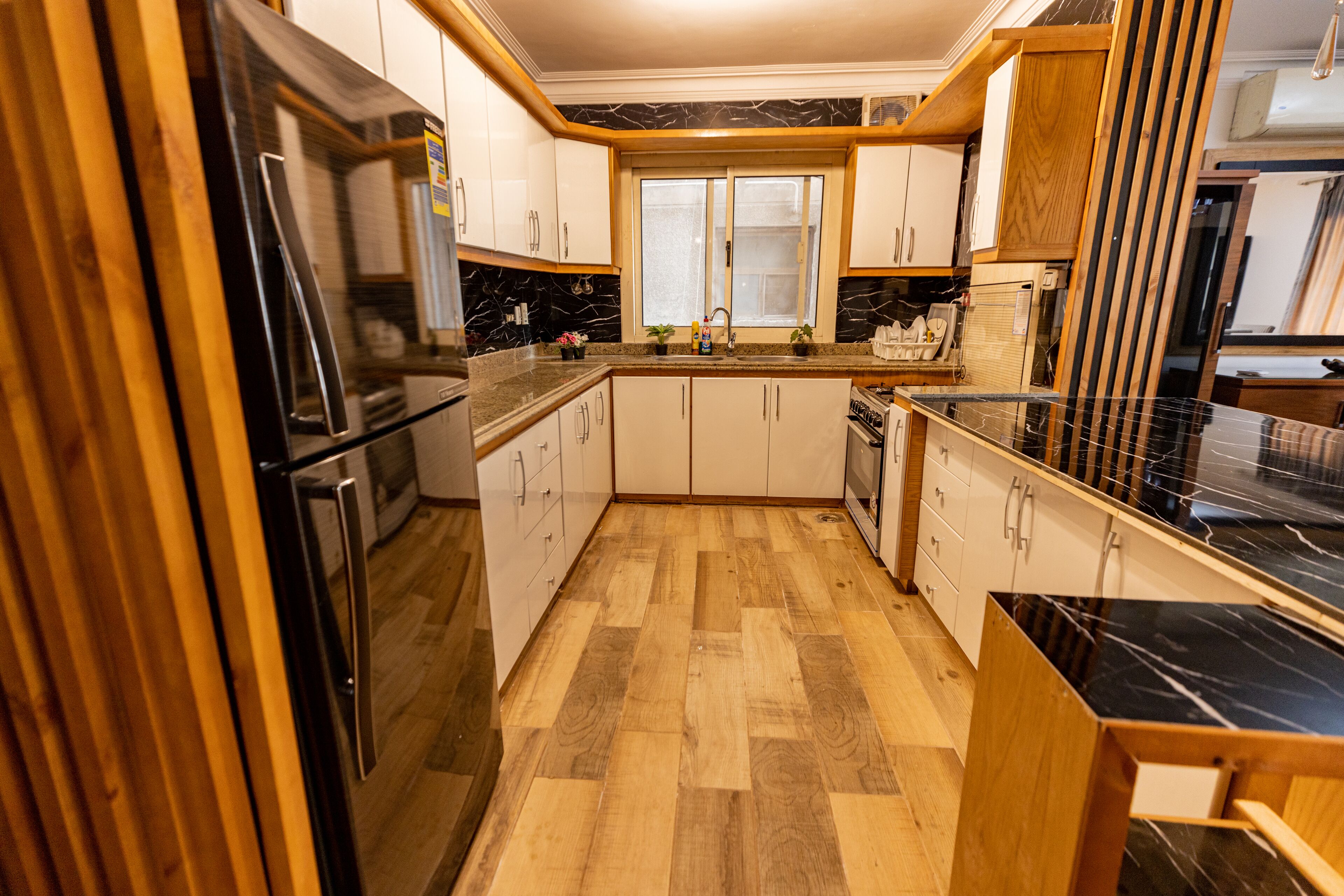 A kitchen with wooden cabinets, a black countertop, and a wooden floor.