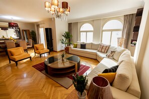 A spacious living room with a sofa, armchairs, a coffee table, and a dining area with chairs and a table. - Oak Orchid Opulent 2 BR Apartment with Walk-in Closet (Cairo)