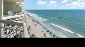 A beachfront hotel with a balcony overlooking a sandy beach and the ocean. - Beautiful oceanfront Condo with direct access to the beach, steps from the sand. (Murrells Inlet)