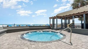 A swimming pool with a view of the ocean, a covered seating area, and a lifeguard tower. - Beautiful oceanfront Condo with direct access to the beach, steps from the sand. (Murrells Inlet)