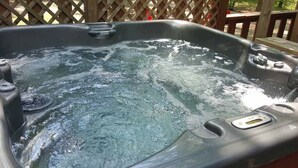 A hot tub with a wooden deck and a lattice fence in the background.