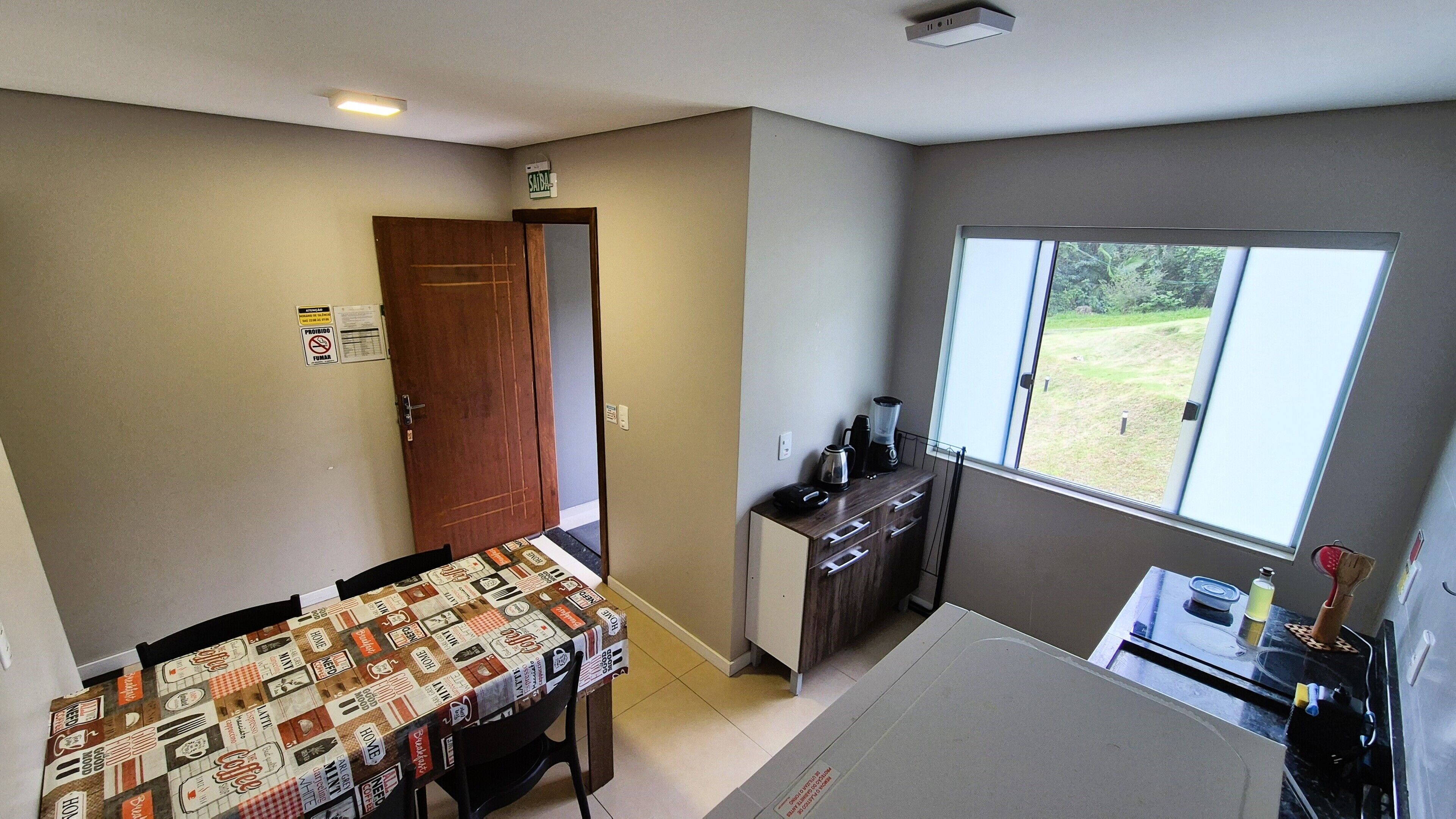 A compact kitchen with a dining area, a window with a view, and a door leading to another room.