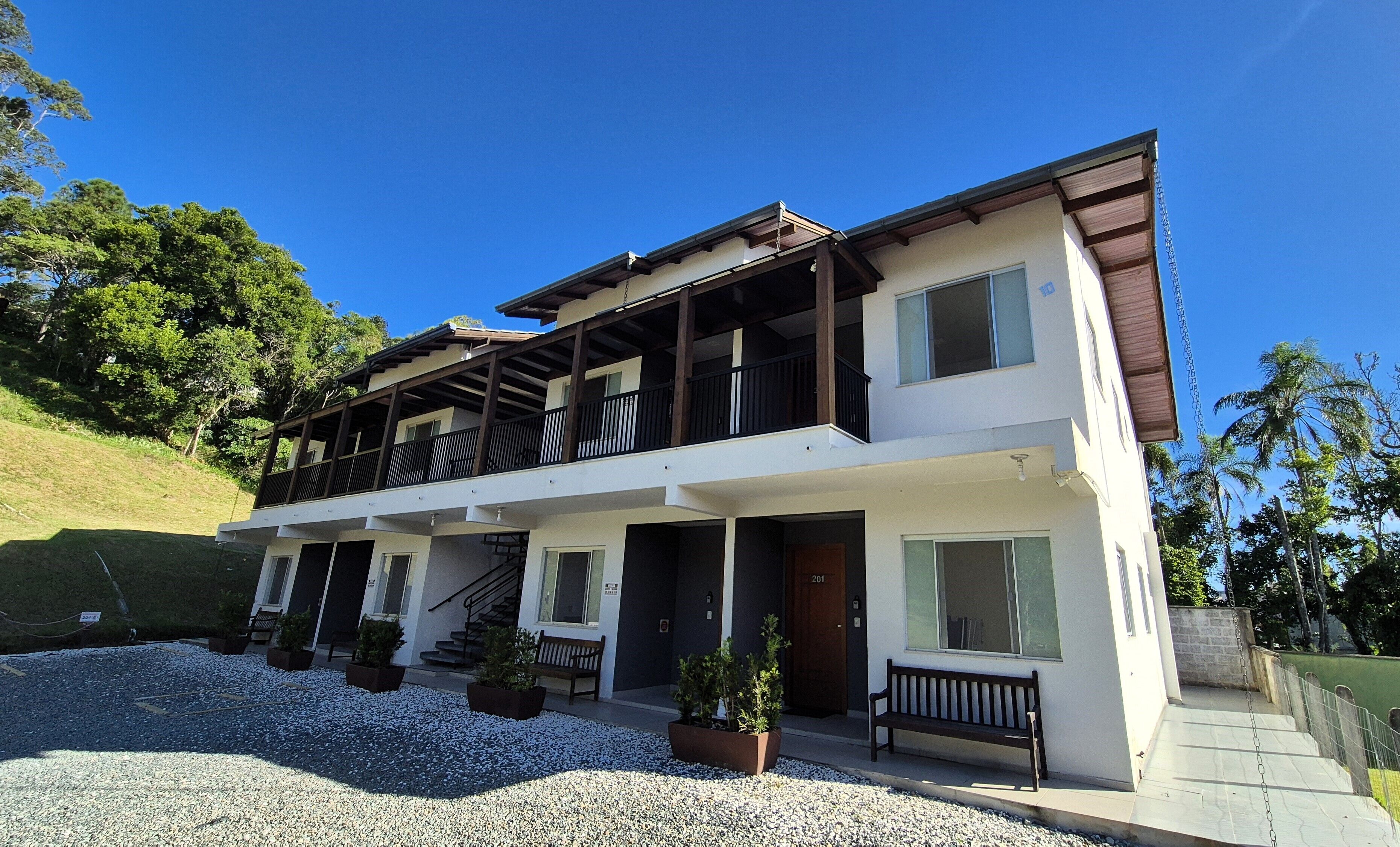 A two-story house with a balcony, a front door, and a staircase leading to the entrance.