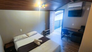 Un dormitorio con una cama, un escritorio, una silla y un equipo de aire acondicionado.