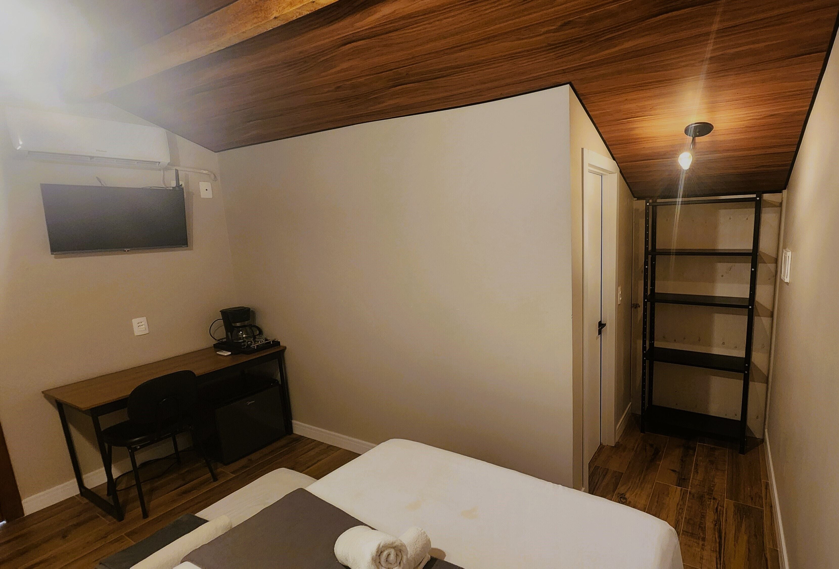 Ein Schlafzimmer mit Bett, Schreibtisch, Stuhl und einer eingebauten Ablagefläche.