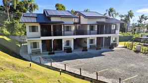Un bâtiment à deux étages doté de panneaux solaires, d’une allée en gravier et d’une cour clôturée.