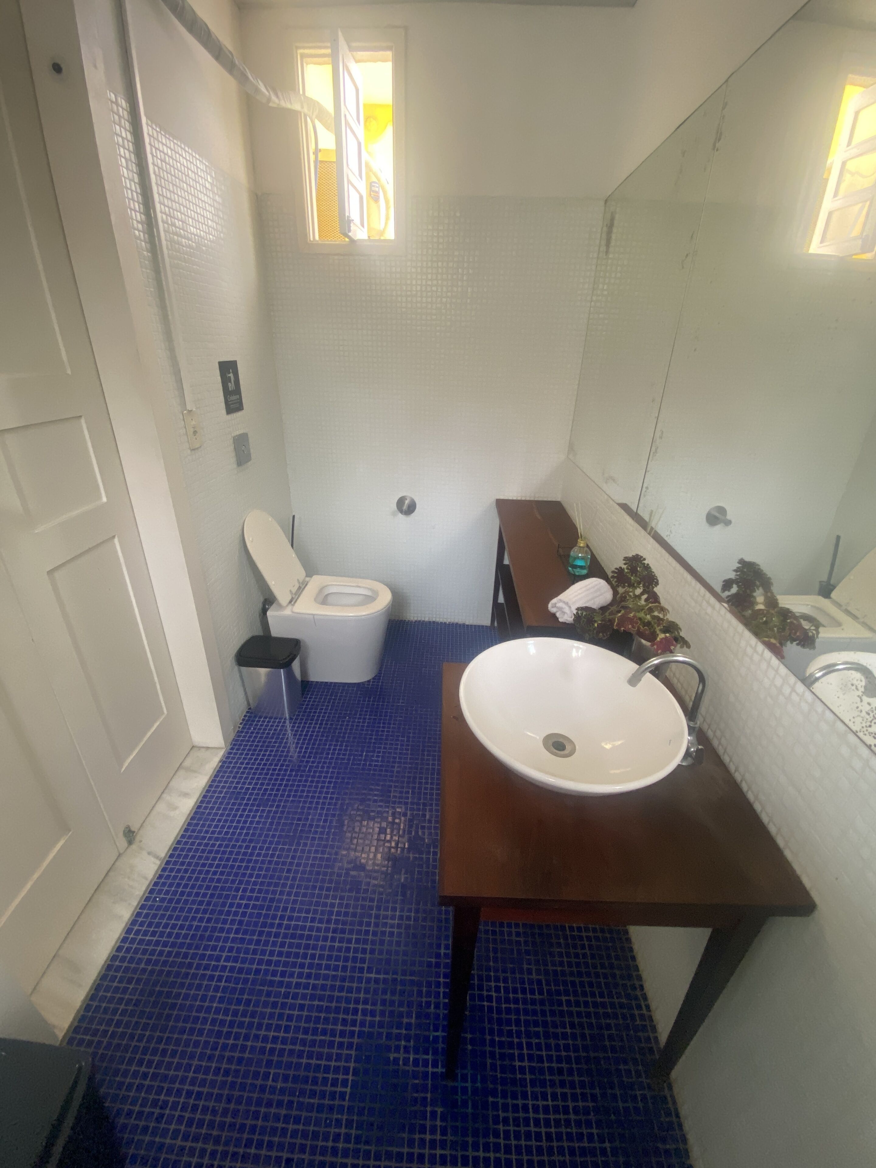 A bathroom with a white toilet, a sink with a mirror, and a blue tiled floor.