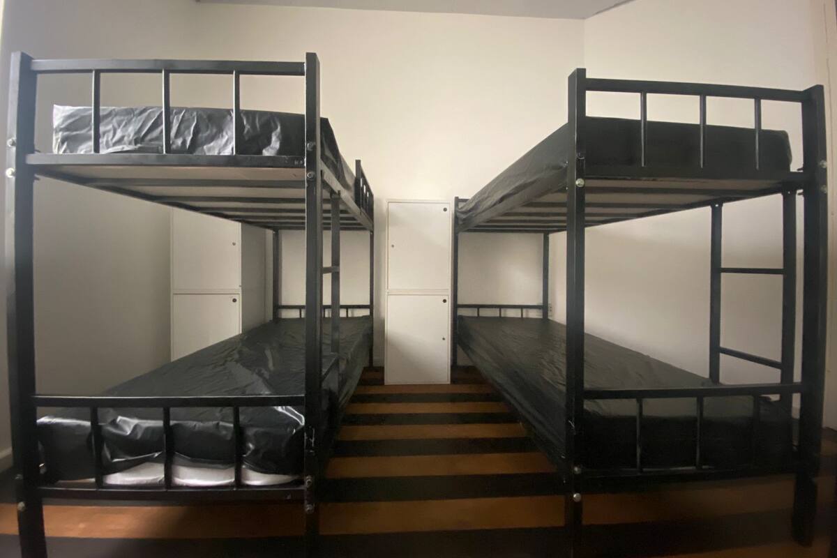 Ein Zimmer mit zwei Etagenbetten, einer kleinen Tür und einem Streifenfußboden.