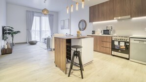 A modern kitchen with wooden cabinets, a built-in oven, a microwave, and a sink. - Placid 1BR at La Cote 5 Palm Jumeirah by Deluxe Holiday Homes (Dubai)
