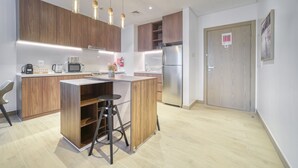 A modern kitchen with wooden cabinets, stainless steel appliances, and pendant lighting. - Placid 1BR at La Cote 5 Palm Jumeirah by Deluxe Holiday Homes (Dubai)