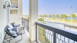 A balcony with a view of a marina, palm trees, and a clear sky. - Placid 1BR at La Cote 5 Palm Jumeirah by Deluxe Holiday Homes (Dubai)