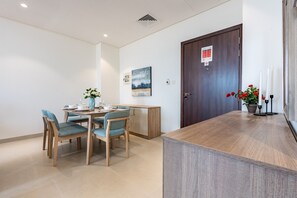 A hotel room with a dining area, a wooden door, and a small table with a vase of flowers.