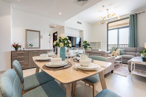 Een moderne eethoek met een houten tafel gedekt voor vier personen, omringd door blauwe stoelen met bekleding.