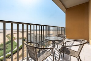 Een balkon met een tafel en twee stoelen, met uitzicht op een stadsbeeld en een woestijnlandschap.