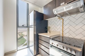 A modern kitchen with a built-in oven, a window with a view, and a small plant on the counter.