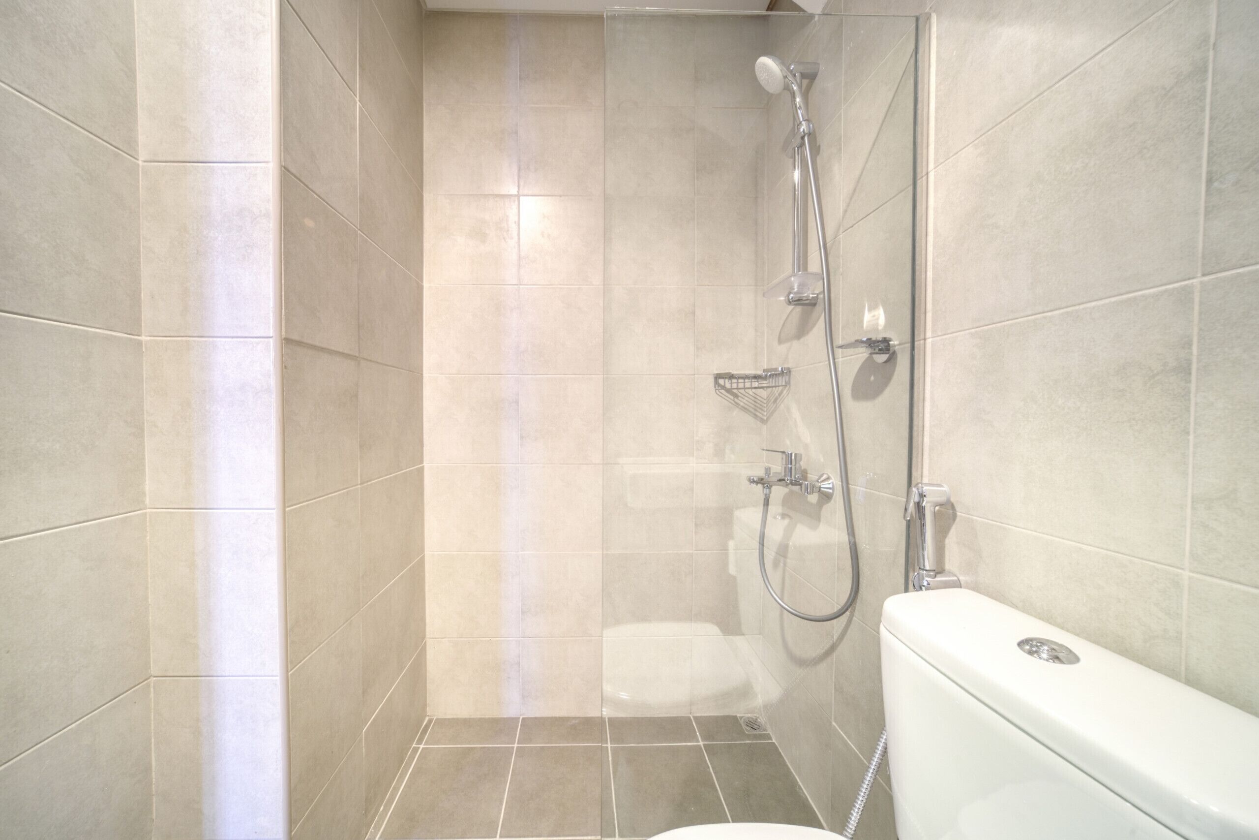 Un baño pequeño y moderno con ducha, inodoro y lavamanos en esquina.