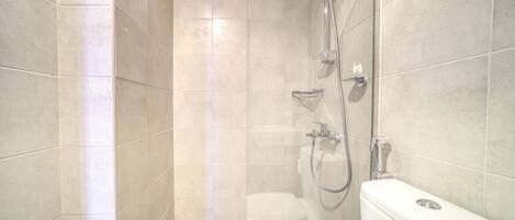 Un baño pequeño y moderno con ducha, inodoro y lavamanos en esquina.