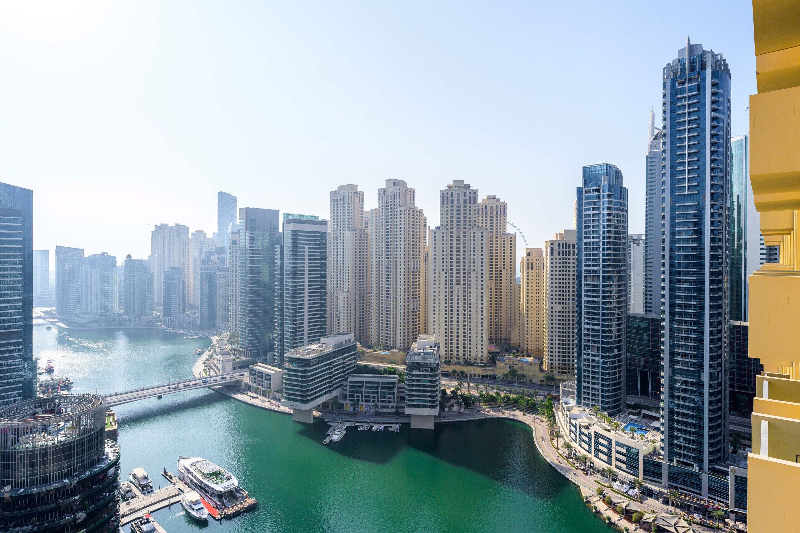 A high-rise urban area with modern buildings, a marina with boats, and a bridge connecting different parts of the city.