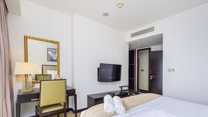 Una camera d'albergo con un letto, una scrivania con una sedia, una televisione e un armadio.
