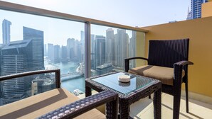 Un balcone con mobili in vimini, un tavolino in vetro e vista sulla città e sul fiume.