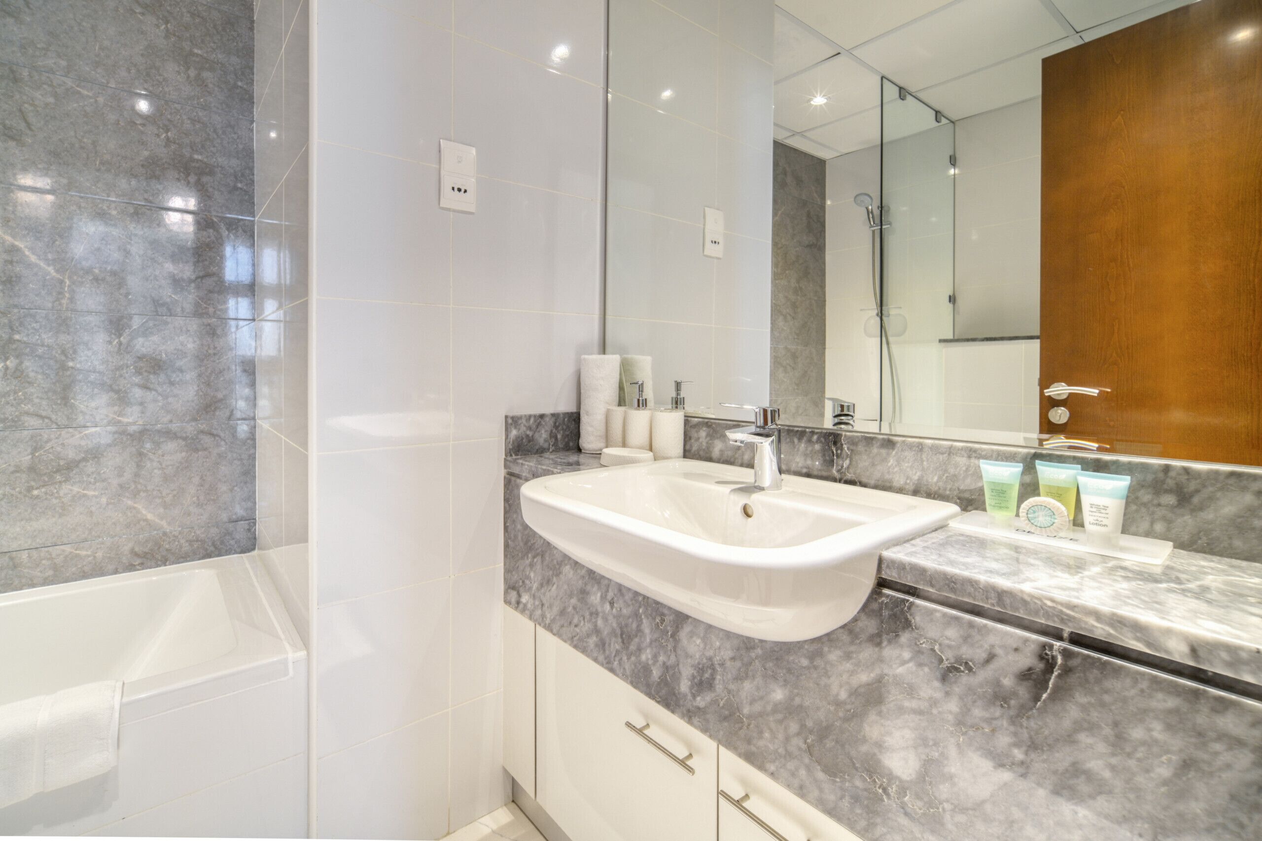 A modern bathroom with a marble sink, a large mirror, and a shower area.