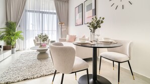 Un salon moderne avec une table de salle à manger ronde, deux chaises, un canapé, une table basse et une plante en pot.