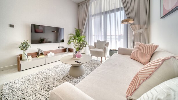 Un salon moderne comprenant un canapé, un fauteuil, une table basse, un téléviseur et de grandes fenêtres avec des rideaux.