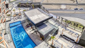 Un espace piscine sur le toit, doté d’une structure en verre, d’un salon avec des sièges et d’une vue sur le paysage urbain environnant.