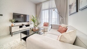 A modern living room with a sofa, coffee table, TV, and a plant. - Spectacular 1BR at Binghatti Avenue Al Jaddaf by Deluxe Holiday Homes (Dubai)