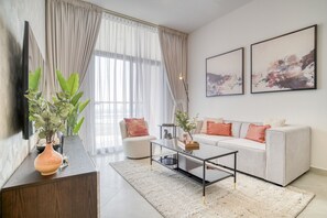 A modern living room with a sofa, coffee table, and a large window with curtains.