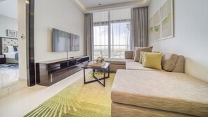 A modern living room with a sofa, a coffee table, a TV, and a balcony view.