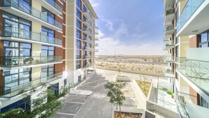 A modern multi-story building with balconies, a parking area, and a view of a desert landscape.