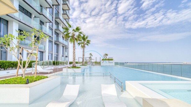 Ett modernt hotell med pool, palmer och utsikt över havet.