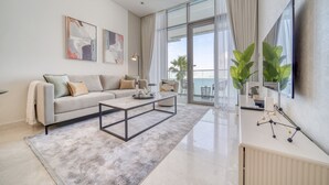 Ein modernes Wohnzimmer mit einer Couch, einem Couchtisch und einem großen Fenster mit Meerblick.